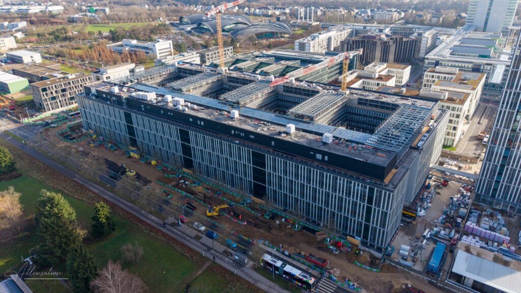 Vue du ciel du bâtiment Jean Monnet en chantier, montrant la structure, les zones de travaux et l’organisation du site.