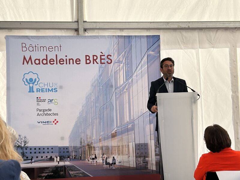Intervenant présentant le projet du bâtiment Madeleine Brès devant une affiche détaillant la future architecture de l’établissement et les partenaires de l’opération.