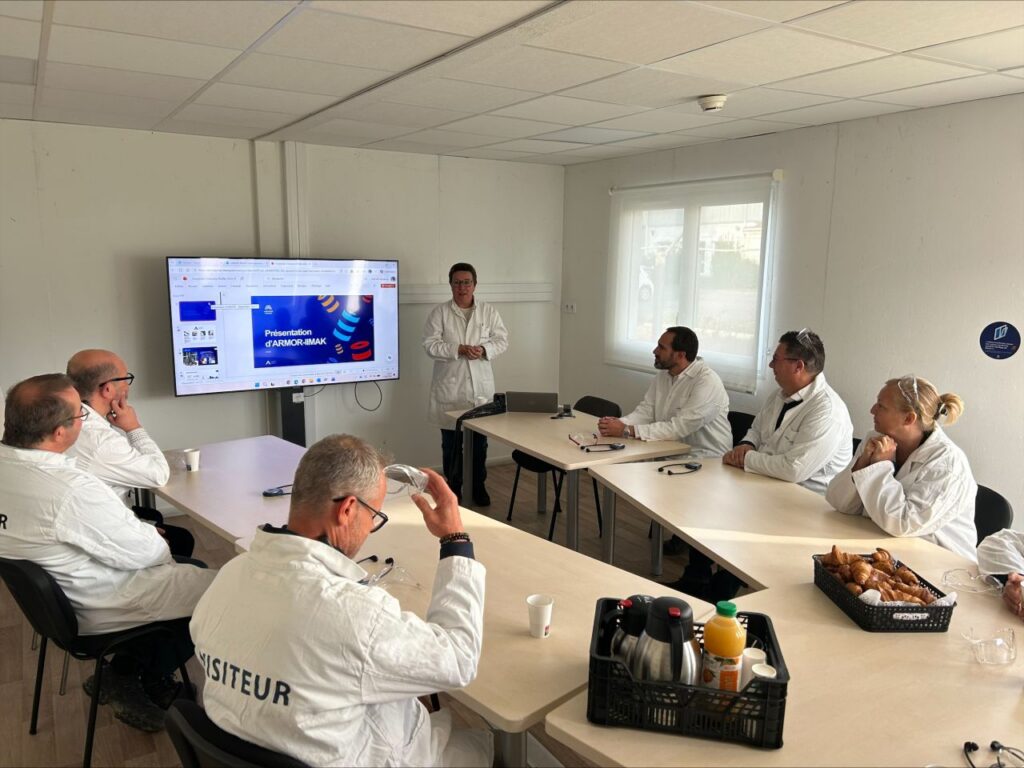 Un intervenant présente le site ARMOR-IIMAK à un groupe de visiteurs réunis dans une salle, à l’aide d’un support projeté intitulé « Présentation d’ARMOR-IIMAK ».