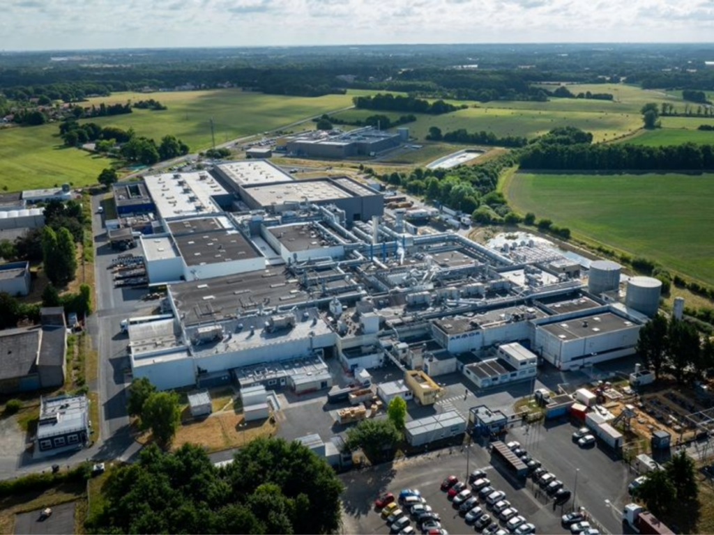 Vue aérienne du site industriel ARMOR-IIMAK, implanté dans un environnement rural et entouré de bâtiments de production, de zones techniques et de champs.